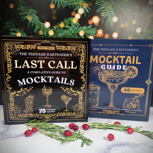 Two cocktail books titled 'Last Call' and 'Mocktail Guide' on a decorative surface with greenery and lights.